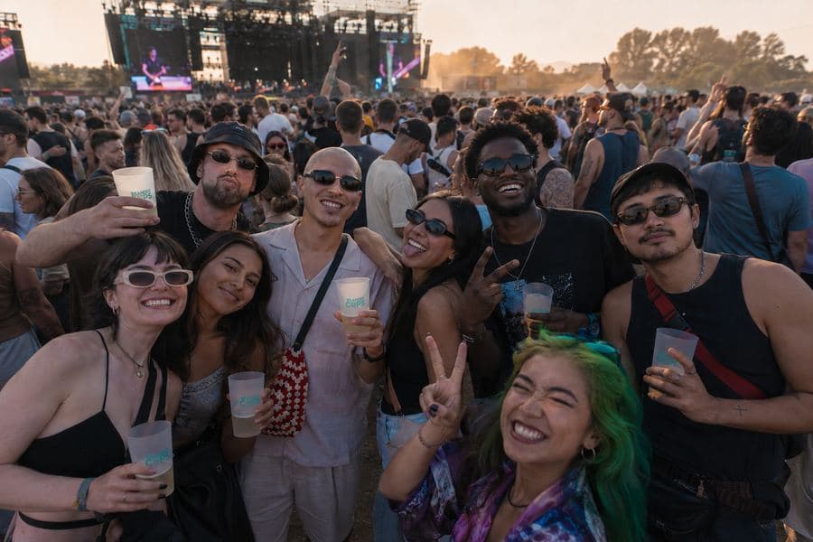 Festival crowd using reusable cups in front of a main stage